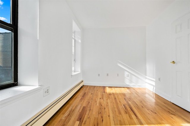 empty room with light wood-type flooring and a baseboard heating unit