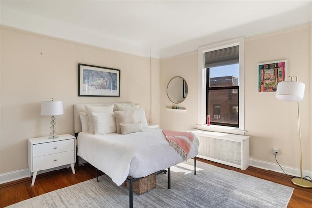 bedroom with crown molding, radiator heating unit, and dark hardwood / wood-style floors