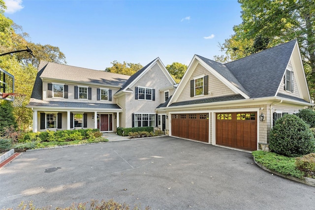 shingle-style home featuring a garage, driveway, and roof with shingles