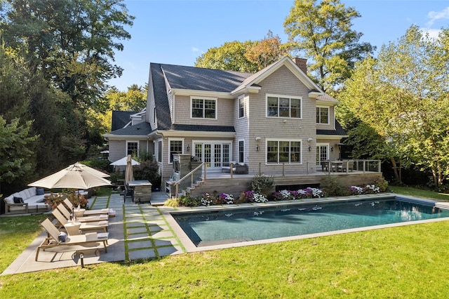 rear view of house featuring a yard, an outdoor pool, french doors, and a wooden deck