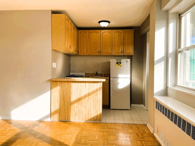 kitchen featuring plenty of natural light, white fridge, backsplash, and radiator