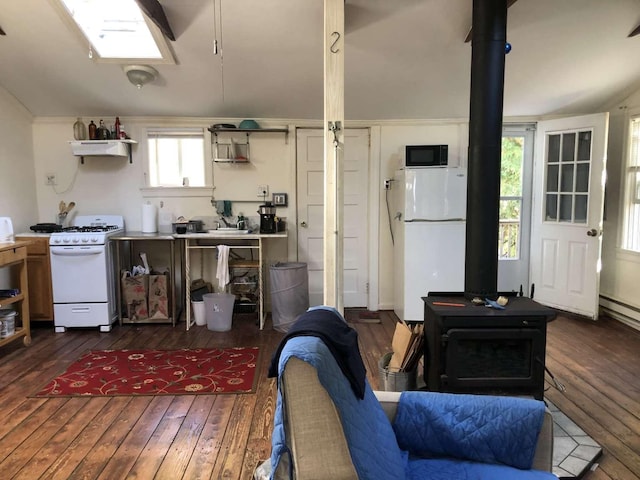 interior space with a wood stove, dark hardwood / wood-style floors, and white appliances