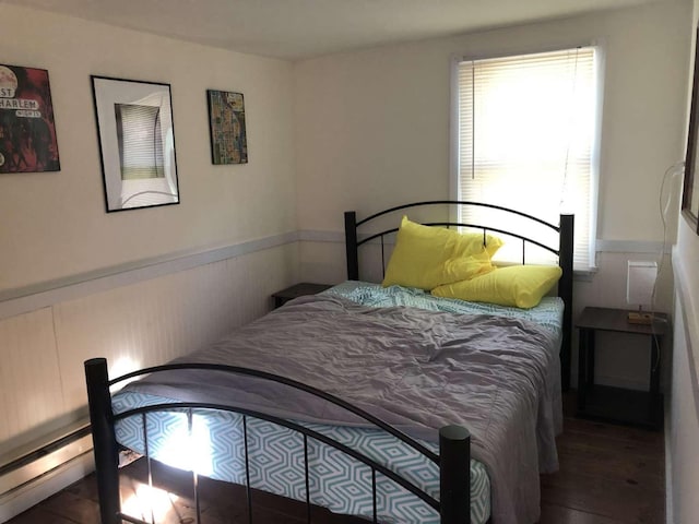 bedroom with dark hardwood / wood-style flooring and baseboard heating