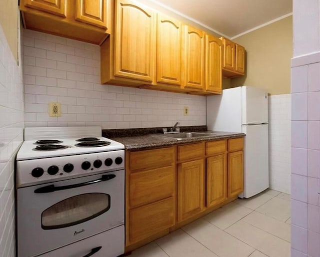 kitchen featuring decorative backsplash, sink, light tile patterned flooring, and white appliances