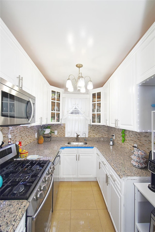 kitchen with stainless steel appliances, sink, decorative light fixtures, an inviting chandelier, and white cabinets