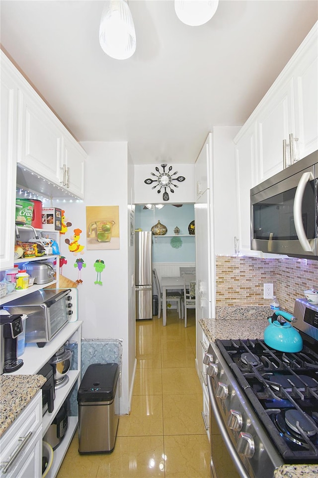 kitchen featuring backsplash, light tile patterned floors, light stone counters, white cabinetry, and stainless steel appliances