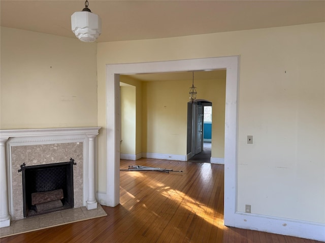 unfurnished living room featuring hardwood / wood-style flooring and a tiled fireplace