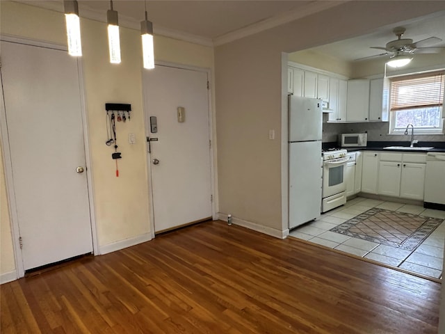 kitchen with sink, white appliances, white cabinetry, ornamental molding, and decorative light fixtures