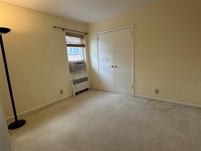 unfurnished bedroom with a closet, light carpet, radiator heating unit, and cooling unit