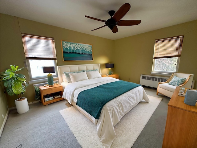 carpeted bedroom featuring multiple windows, radiator, and ceiling fan