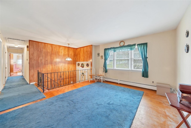 unfurnished room featuring wood walls, light wood-type flooring, and a baseboard radiator