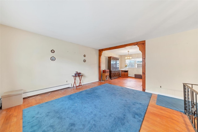 spare room featuring a chandelier, a baseboard radiator, and hardwood / wood-style flooring