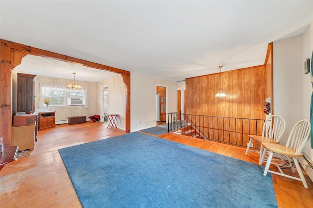 interior space with cooling unit, wooden walls, wood-type flooring, a baseboard radiator, and a notable chandelier