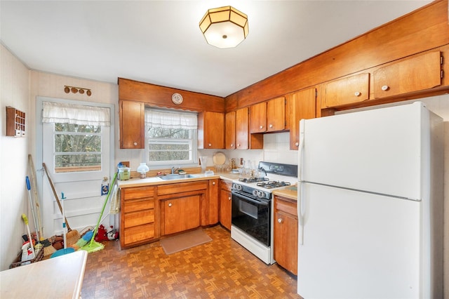 kitchen with dark parquet floors, white appliances, and sink