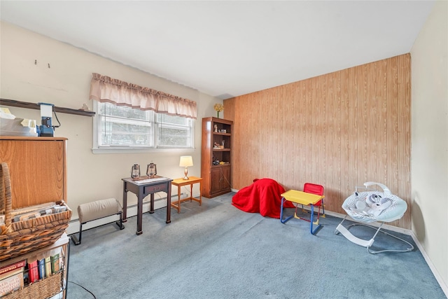 sitting room with wooden walls, carpet, and a baseboard heating unit