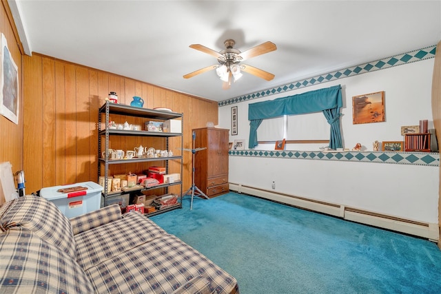 sitting room featuring carpet, ceiling fan, baseboard heating, and wooden walls