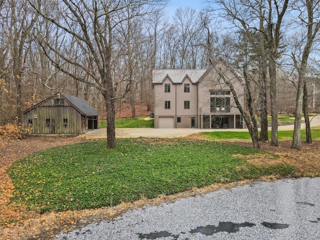 view of front of home featuring a garage, an outbuilding, and a front lawn