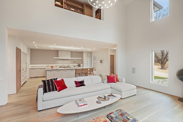 living room with sink, a towering ceiling, and light wood-type flooring