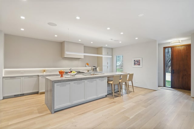 kitchen featuring a large island, white cabinetry, and light wood-type flooring