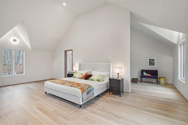 bedroom featuring multiple windows, light hardwood / wood-style flooring, and lofted ceiling