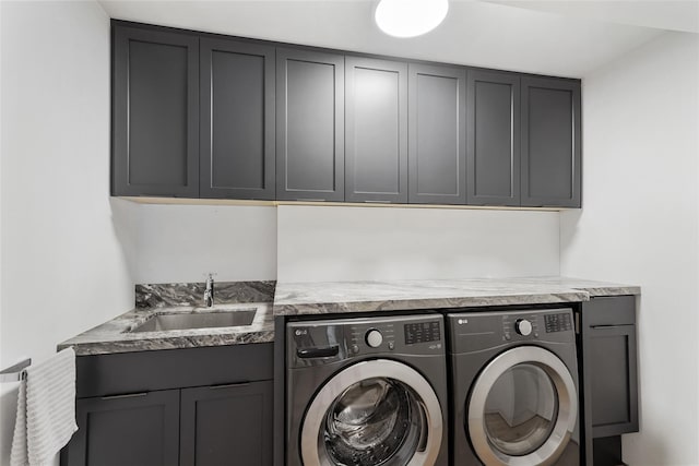 clothes washing area featuring washer and dryer, cabinets, and sink