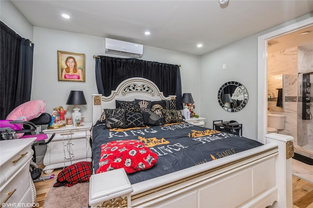 bedroom with wood-type flooring, an AC wall unit, and ensuite bath