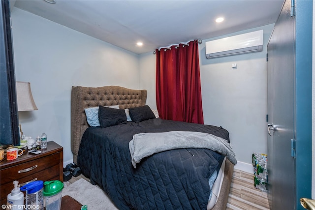 bedroom featuring a wall unit AC and light hardwood / wood-style flooring