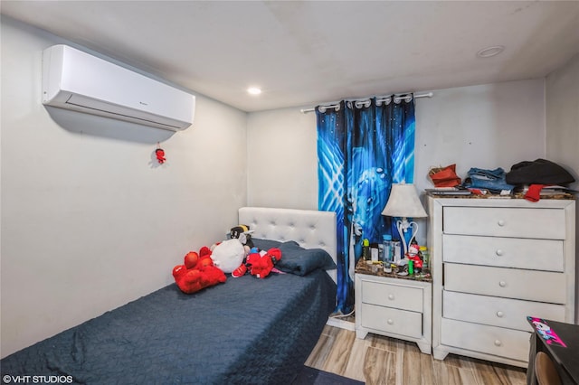 bedroom with a wall unit AC and light hardwood / wood-style flooring