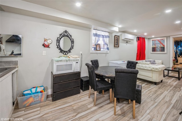 dining room with an AC wall unit and light hardwood / wood-style floors