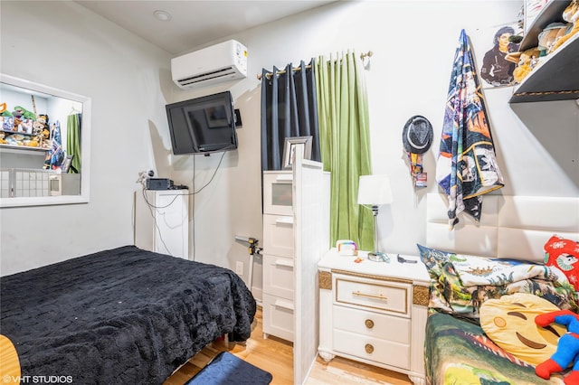 bedroom with a wall mounted air conditioner and light hardwood / wood-style flooring