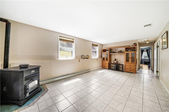 unfurnished living room featuring a wood stove, a baseboard heating unit, and light tile patterned floors