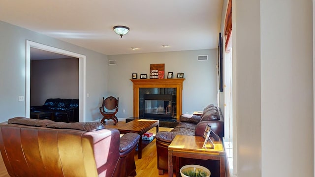 living room featuring a tiled fireplace and light hardwood / wood-style flooring