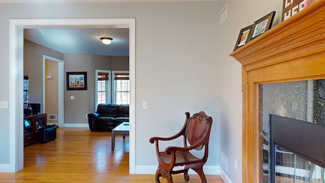 sitting room with light wood-type flooring and a tiled fireplace