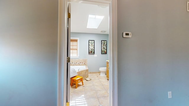 corridor with light tile patterned flooring and a skylight