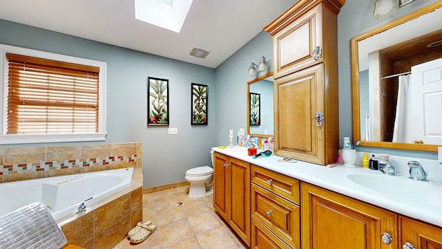 bathroom with vanity, a skylight, tile patterned flooring, a relaxing tiled tub, and toilet