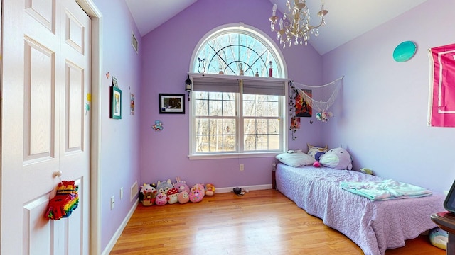 bedroom featuring an inviting chandelier, light wood-type flooring, and vaulted ceiling