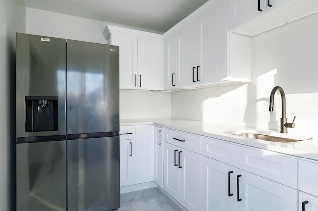 kitchen featuring stainless steel fridge with ice dispenser, white cabinetry, and sink