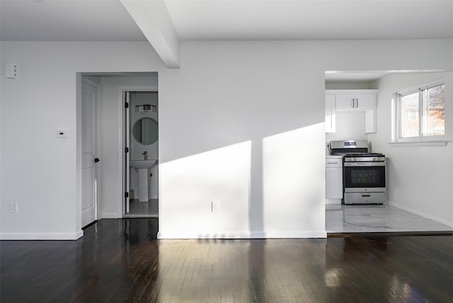 kitchen featuring gas stove, stacked washer and dryer, white cabinets, and dark hardwood / wood-style floors