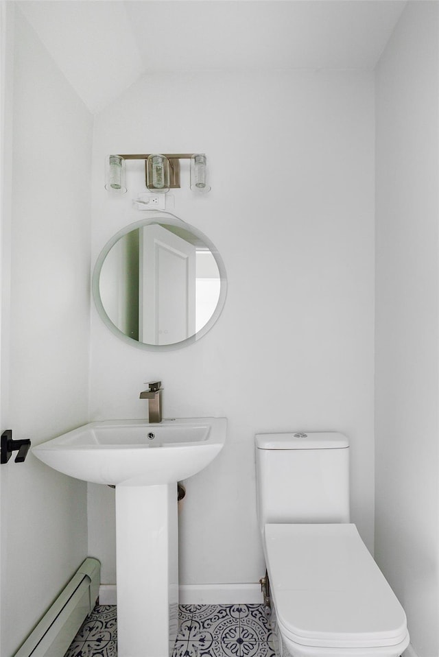 bathroom with tile patterned floors, vaulted ceiling, toilet, and a baseboard heating unit