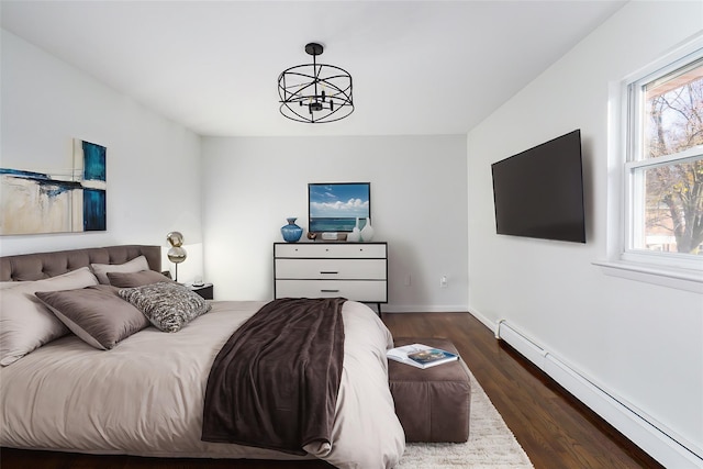 bedroom featuring a chandelier, dark wood-type flooring, baseboard heating, and multiple windows