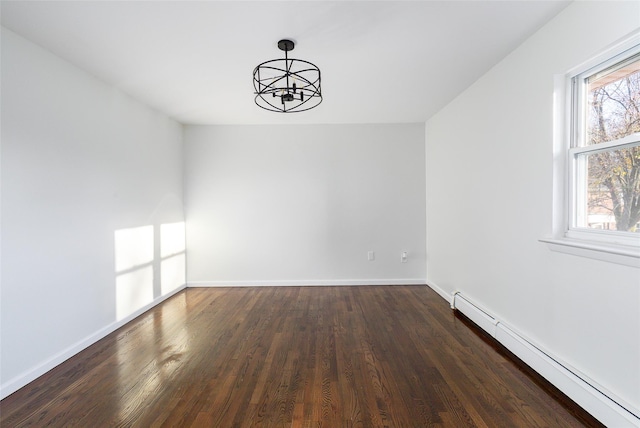 empty room featuring dark hardwood / wood-style flooring, a chandelier, and a baseboard heating unit