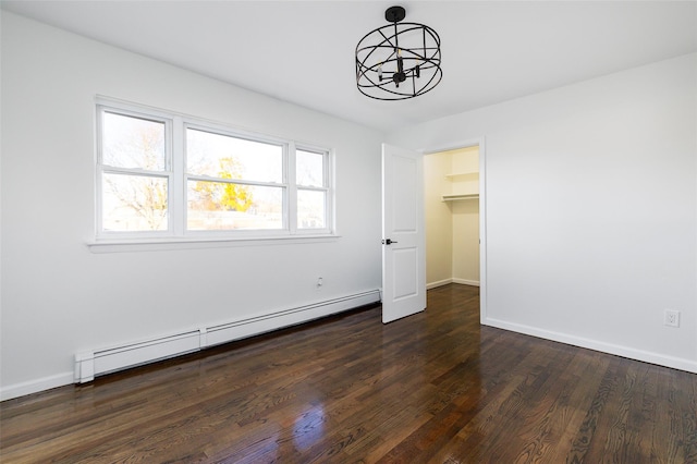 interior space featuring multiple windows, a spacious closet, dark hardwood / wood-style floors, and a baseboard heating unit