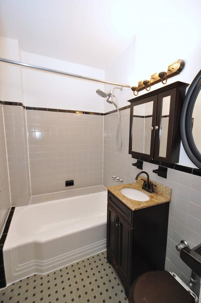 bathroom featuring vanity, tiled shower / bath combo, tile walls, and tile patterned flooring