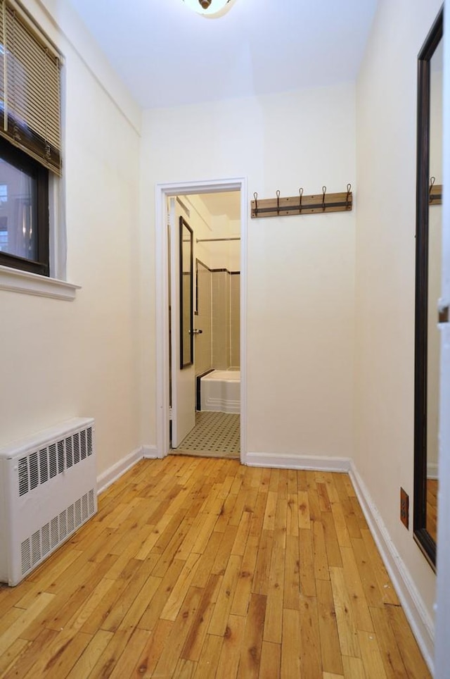 corridor featuring radiator heating unit and light hardwood / wood-style floors