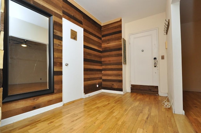 interior space with wooden walls, light hardwood / wood-style flooring, and ceiling fan