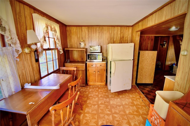 339 Mountain Lake Rd, Andes, NY 13731 - kitchen featuring freestanding refrigerator, stainless steel microwave, wood walls, brown cabinets, and crown molding