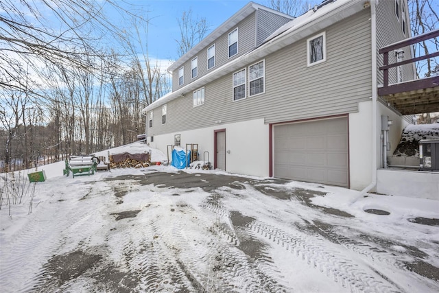 snow covered back of property featuring a garage