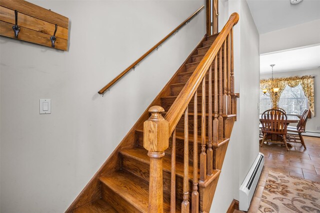 staircase with a baseboard radiator and an inviting chandelier