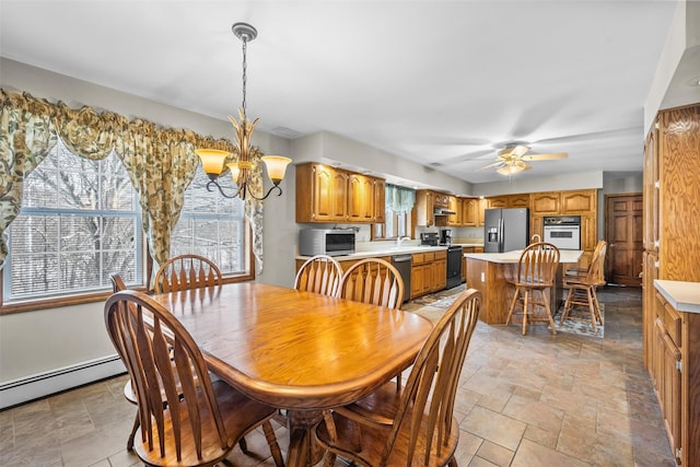 dining room with stone finish floor, a baseboard heating unit, and ceiling fan with notable chandelier