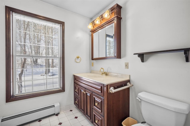 half bathroom featuring vanity, baseboard heating, baseboards, and toilet